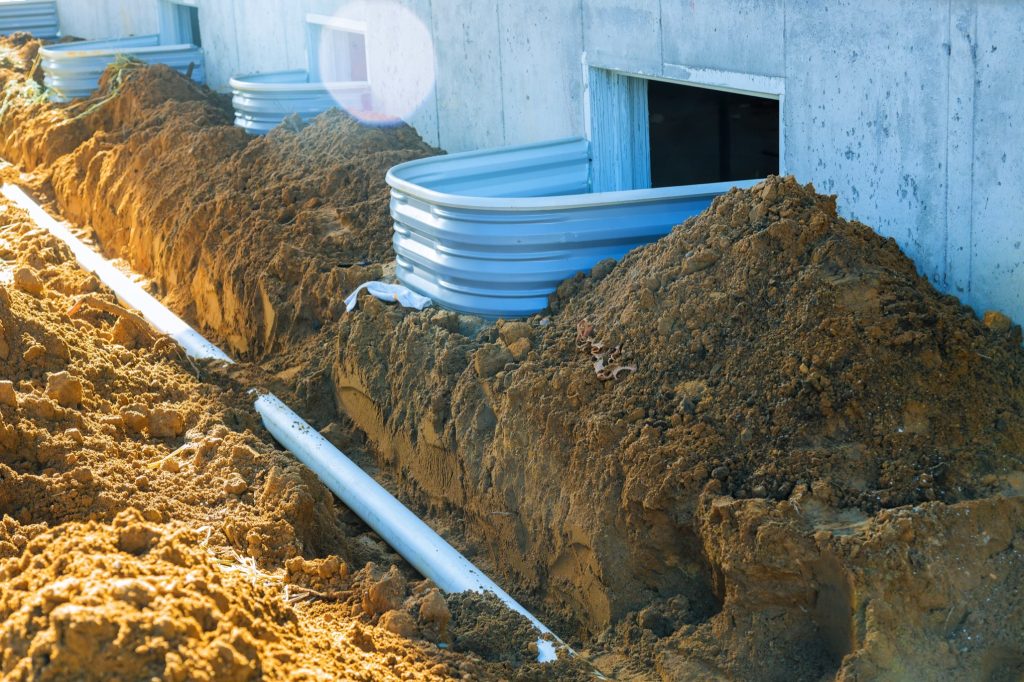 Plastic piping and a rainpipe against and around the a drain pipe in ground house