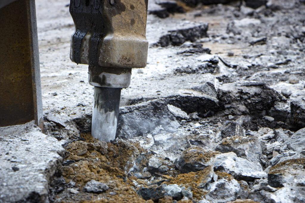 Excavator breaking and drilling the concrete road for repairing close up